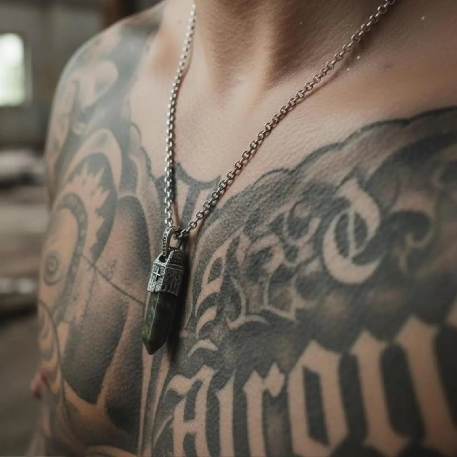 Close-up photograph of natural Moss Agate gemstone pendant featuring soft green moss-like patterns inside crystal, handcrafted into a sterling silver vintage compass design for men’s nautical jewelry collections.