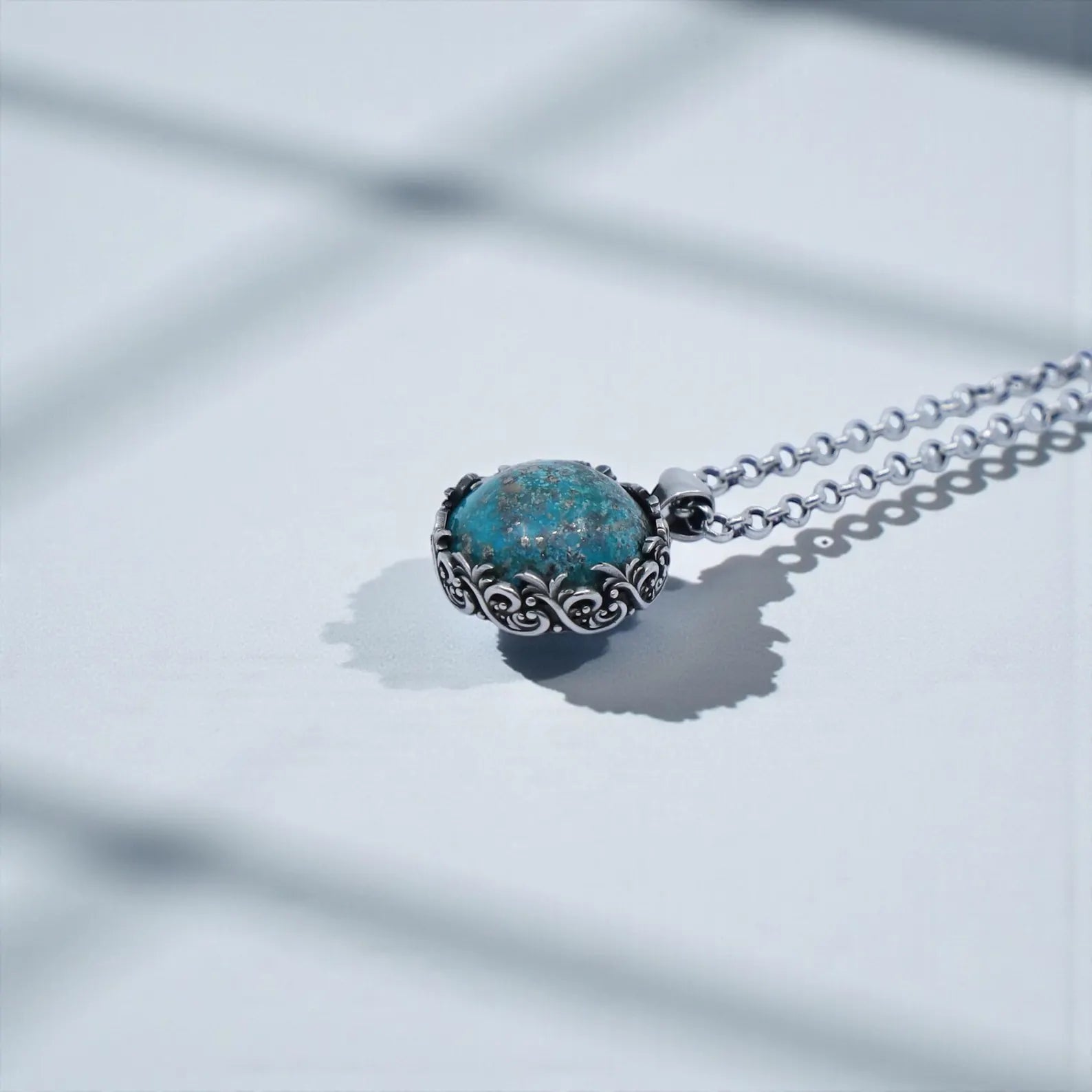 Vintage round turquoise pendant in handcrafted sterling silver featuring elaborate baroque leaf patterns and a hand-polished blue stone with natural matrix; a meaningful necklace representing luck, grounding, and spiritual wisdom, designed especially for men who value detailed, artisan-made gemstone jewelry.