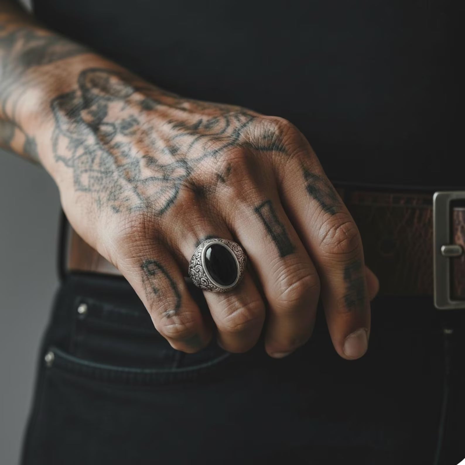 Handcrafted sterling silver black onyx men’s signet ring displayed on a tattooed hand, showcasing the bold vintage baroque engravings and polished natural onyx gemstone, designed as a masculine statement accessory and personalized gift.